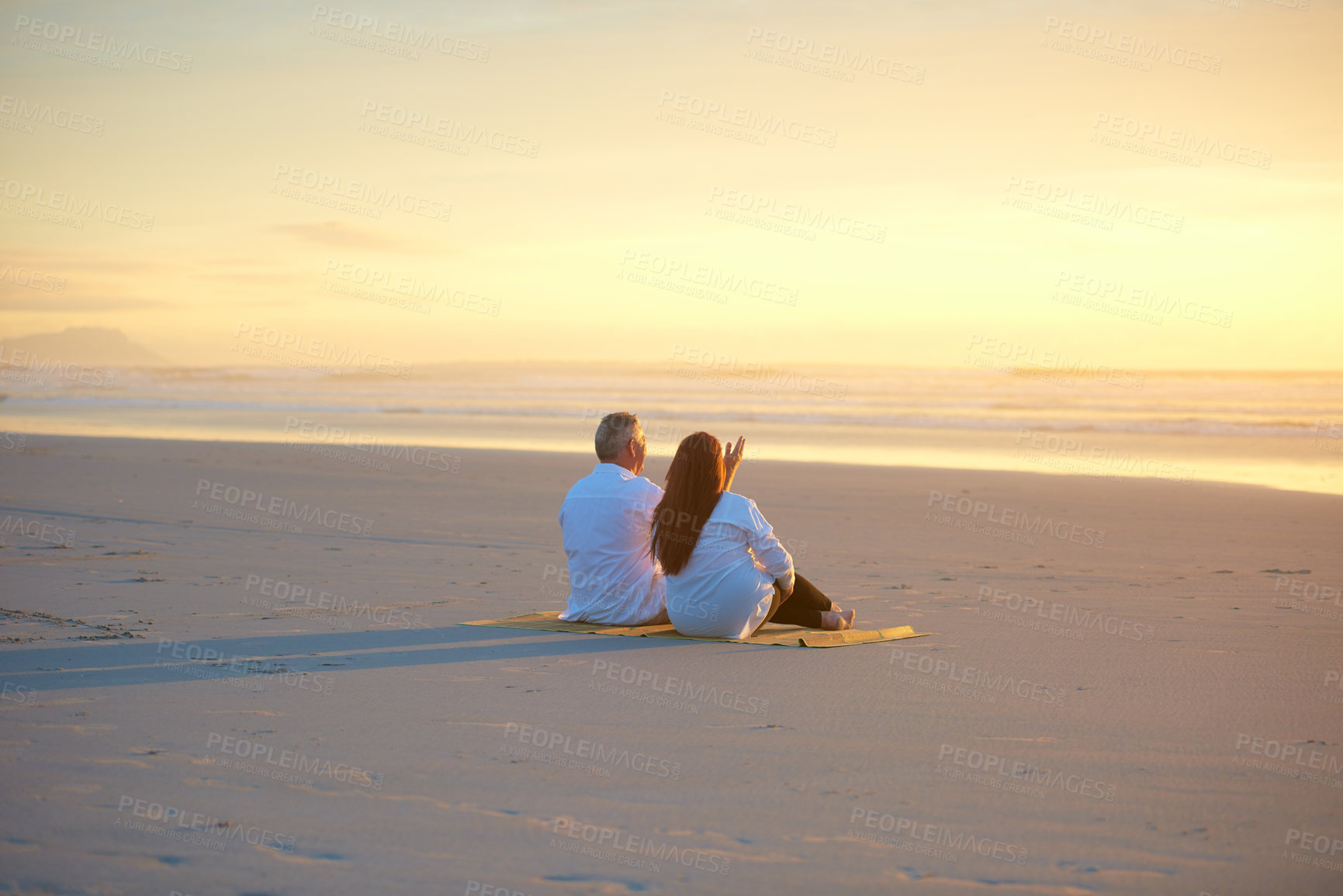 Buy stock photo Shot of a mature couple relaxing together on the beach