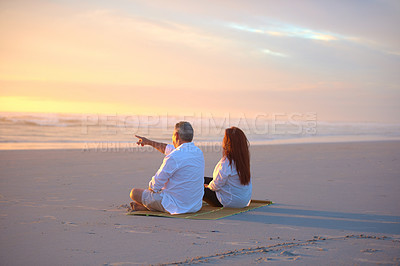 Buy stock photo Shot of a mature couple relaxing together on the beach