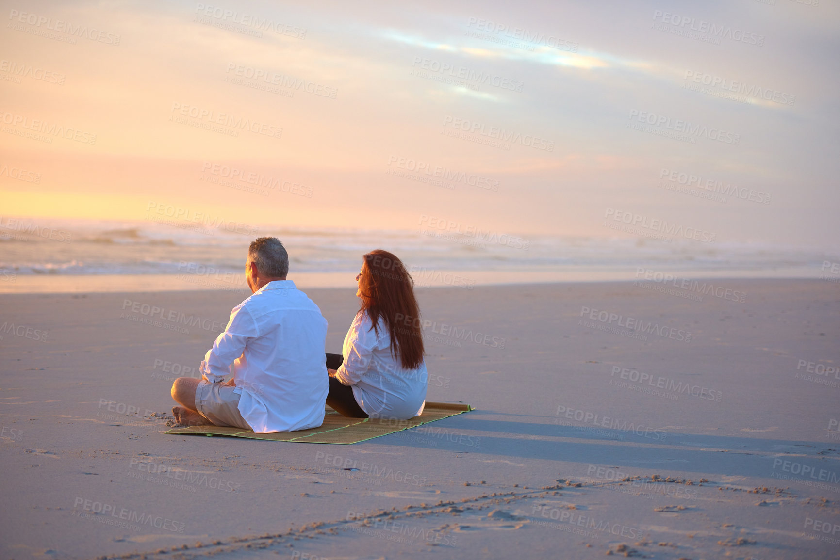 Buy stock photo Shot of a mature couple relaxing together on the beach