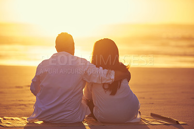 Buy stock photo Rearview shot of an affectionate mature couple enjoying the sunset while sitting on the beach