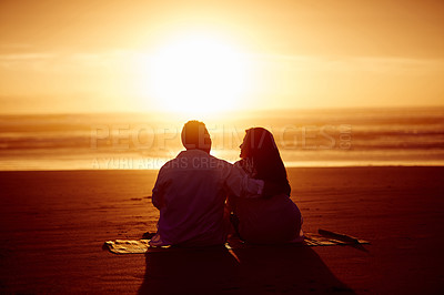 Buy stock photo Rearview shot of an affectionate mature couple enjoying the sunset while sitting on the beach