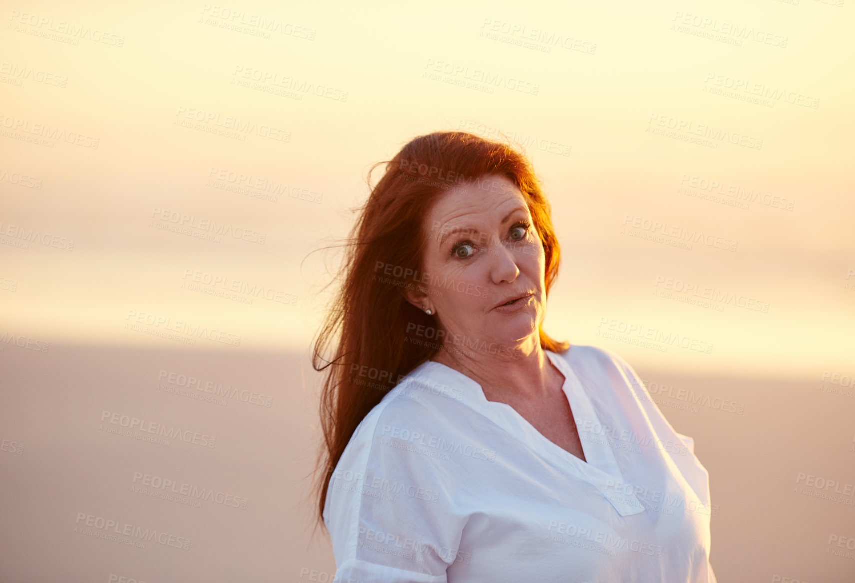 Buy stock photo Shot of mature woman standing on the beach at sunset