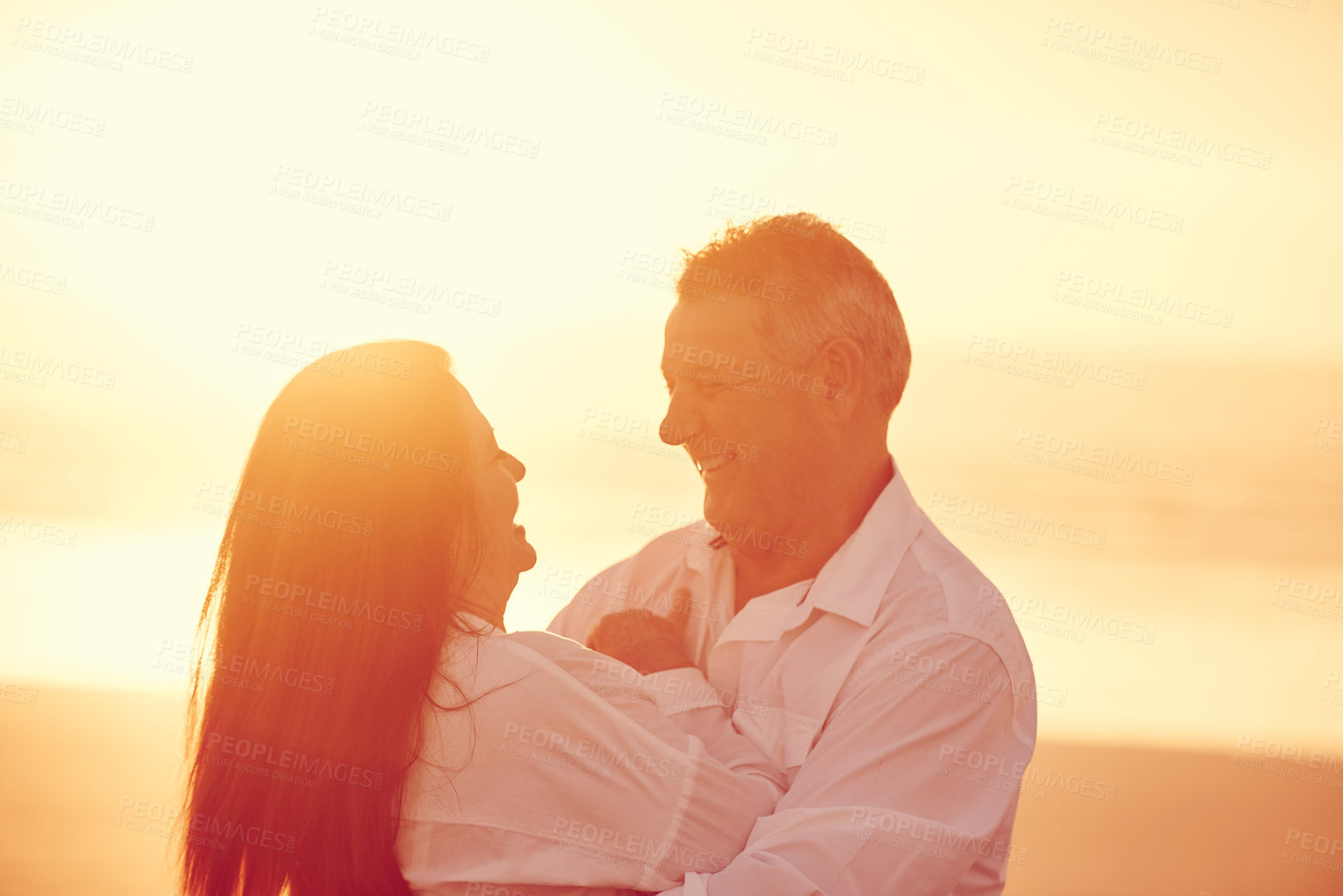 Buy stock photo Cropped shot of an affectionate mature couple embracing on the beach at sunset