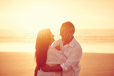 Buy stock photo Cropped shot of an affectionate mature couple embracing on the beach at sunset