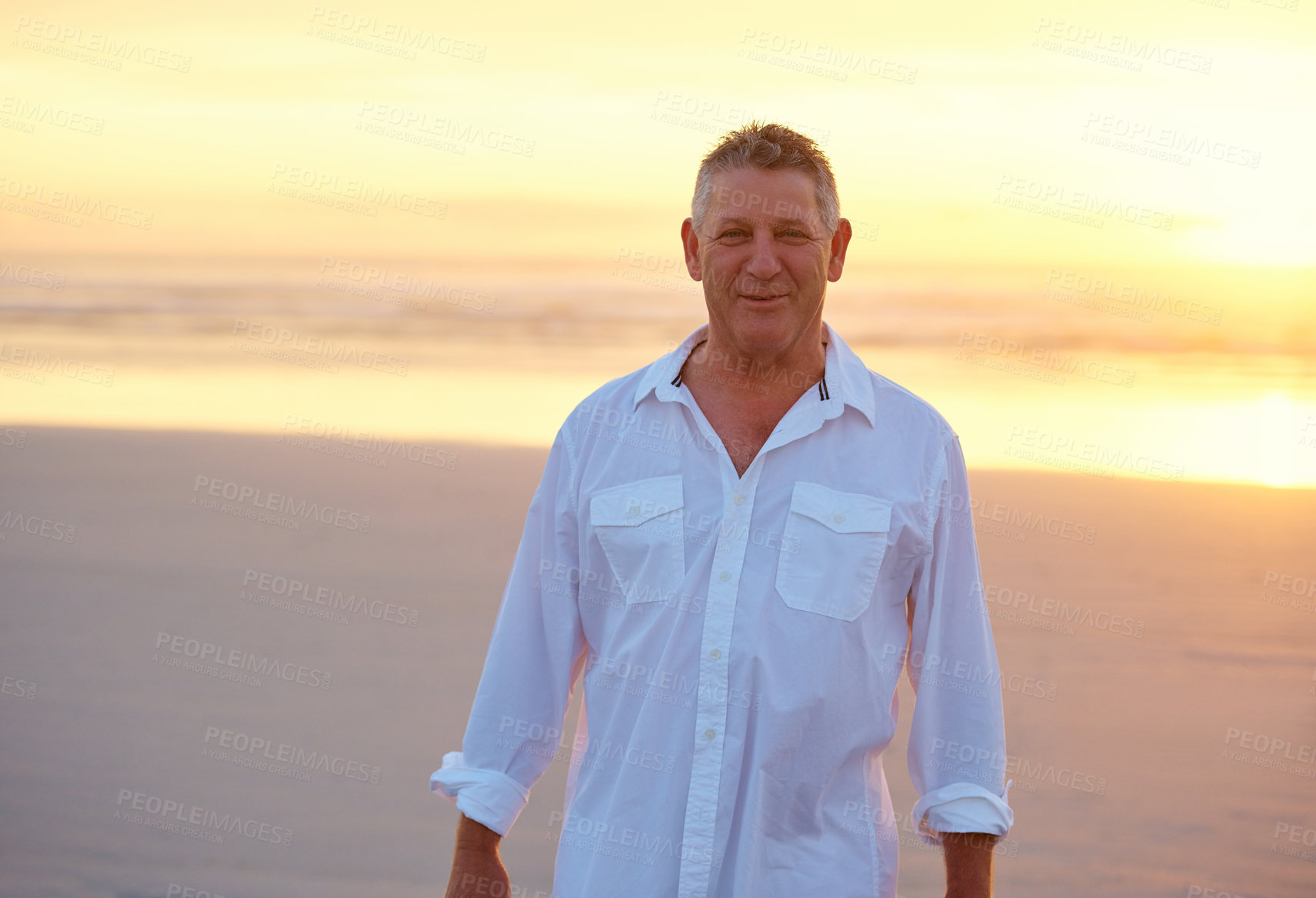 Buy stock photo Shot of mature man standing on the beach at sunset