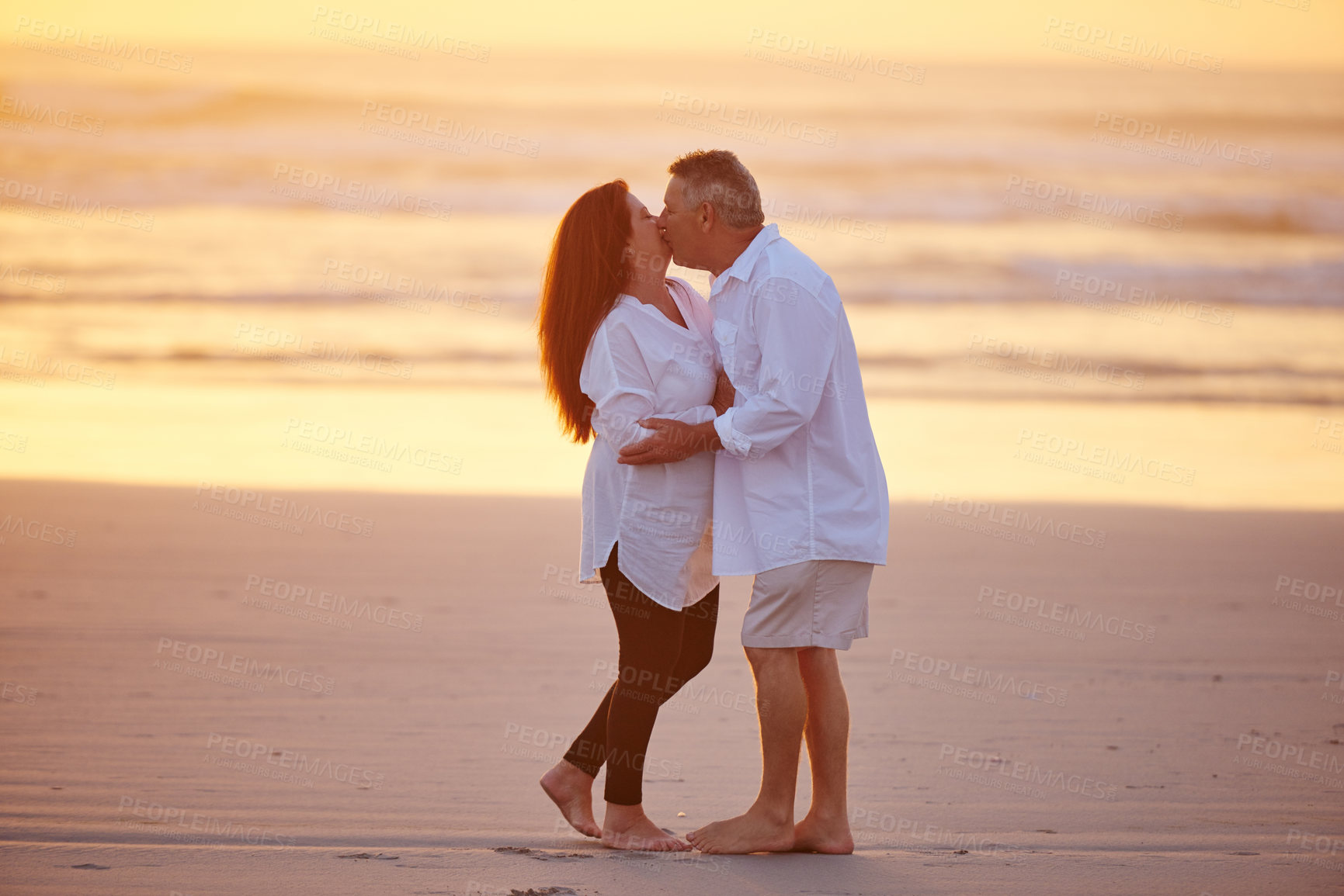 Buy stock photo Shot of a mature couple kissing on the beach