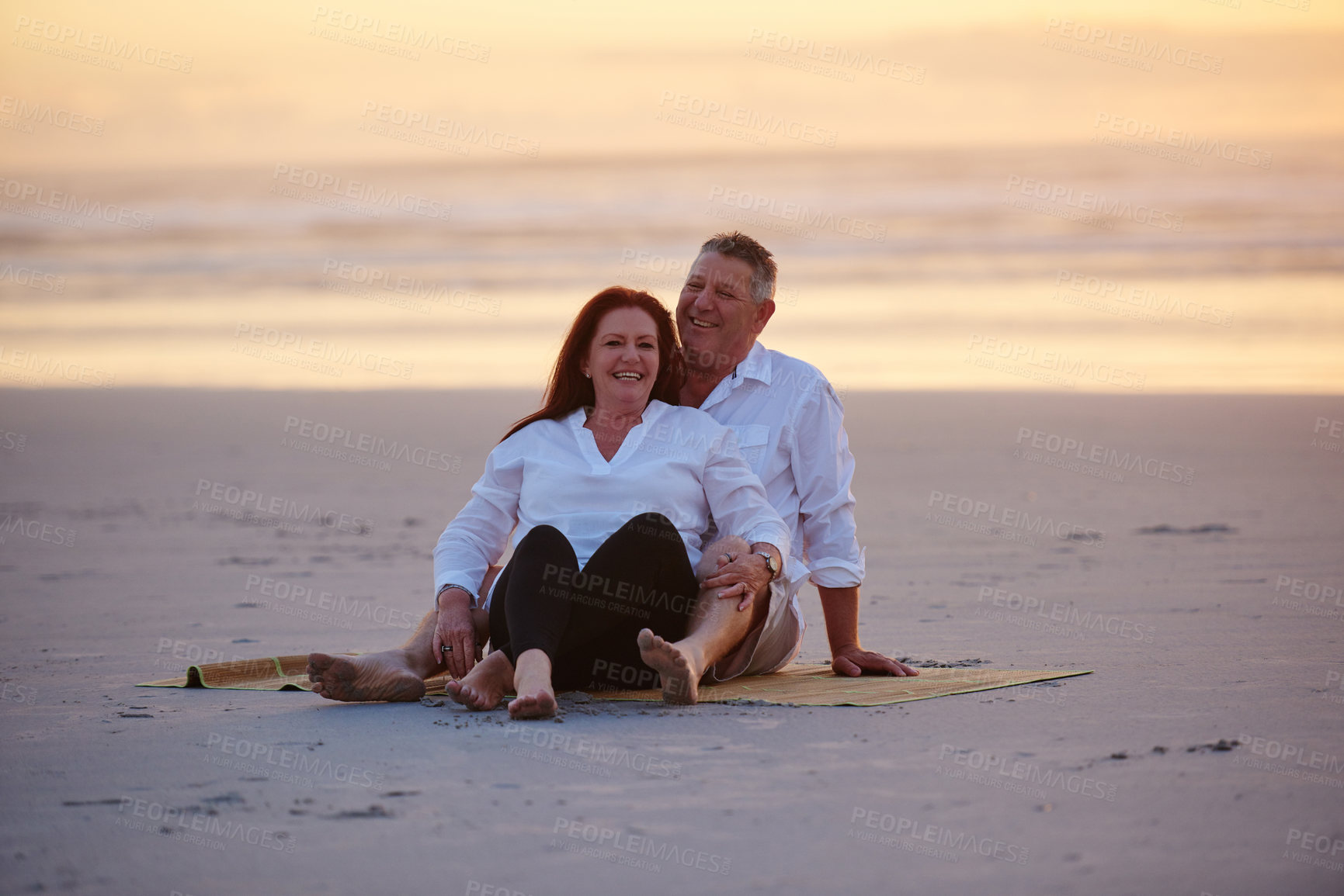 Buy stock photo Shot of a mature couple relaxing together on the beach