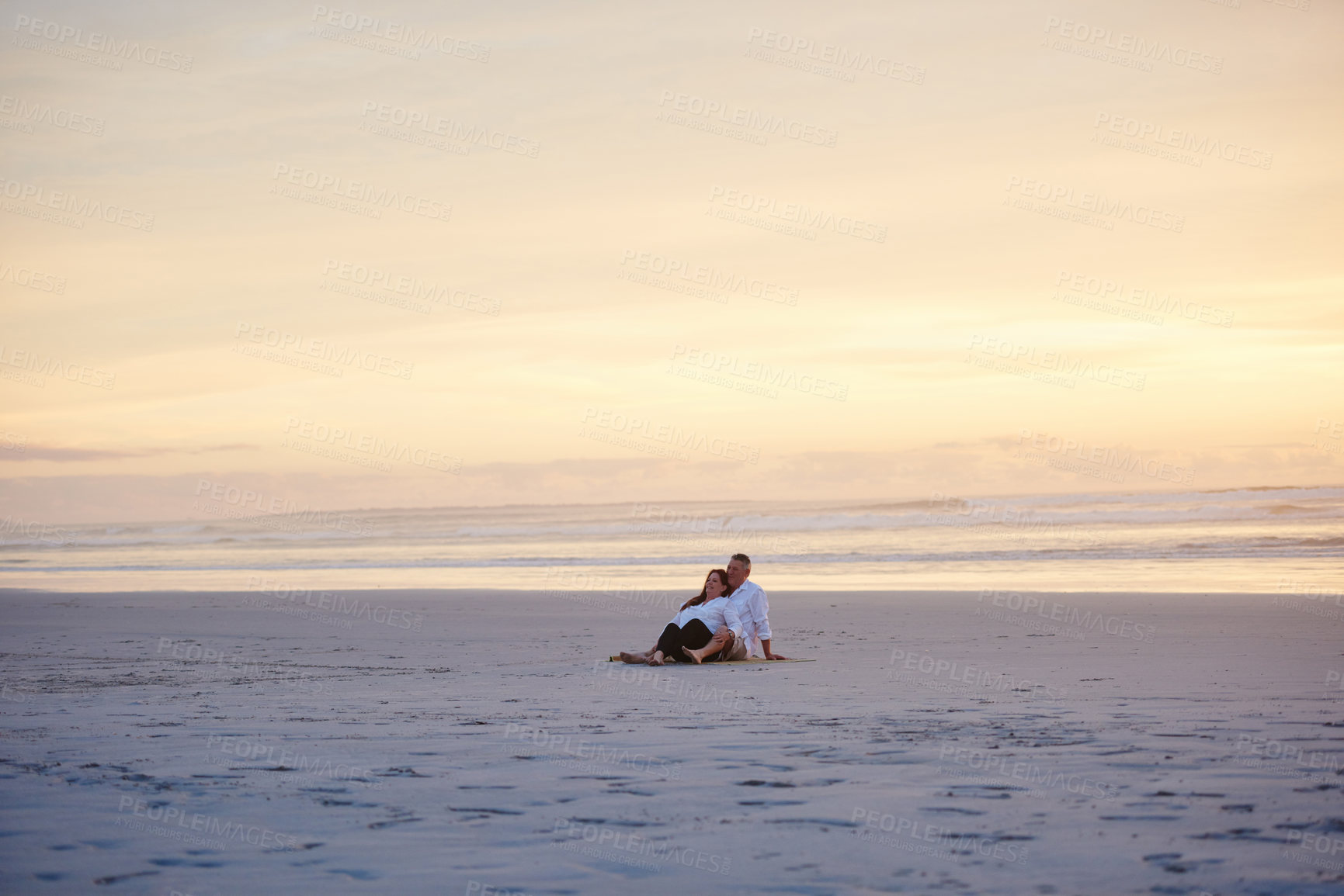 Buy stock photo Shot of a mature couple relaxing together on the beach