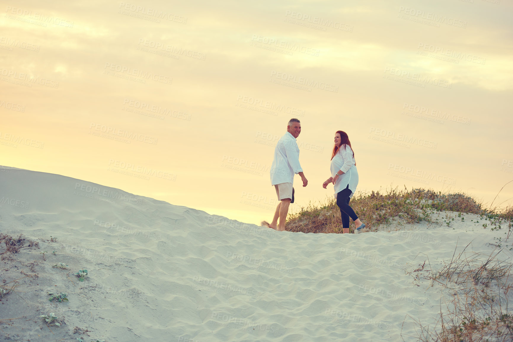 Buy stock photo Shot of mature people standing on a sand dune at the beach