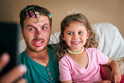 Buy stock photo Shot of a father and his little daughter taking a selfie together while playing dress-up at home