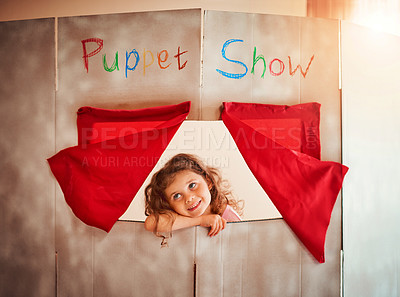 Buy stock photo Shot of an adorable little girl standing in the window of a puppet show theatre at home