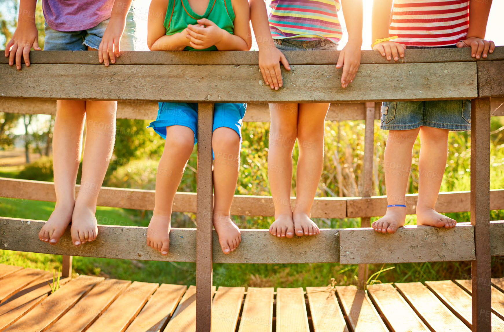 Buy stock photo Children, legs and outdoor on bridge for fun, barefeet and group for development in park. Kids, friends together and feet for support in nature, relationship and playing in backyard for bonding