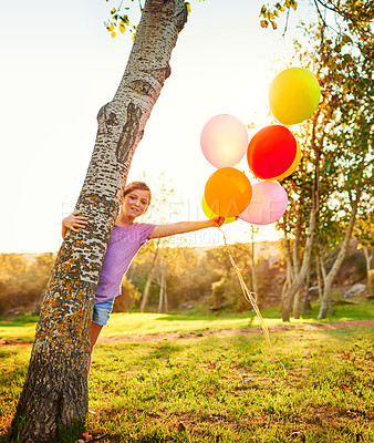 Buy stock photo Portrait of a little girl playing with a bunch of balloons outdoors
