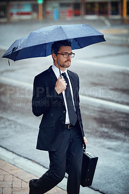 Buy stock photo Shot of a mature businessman holding an umbrella while out in the city
