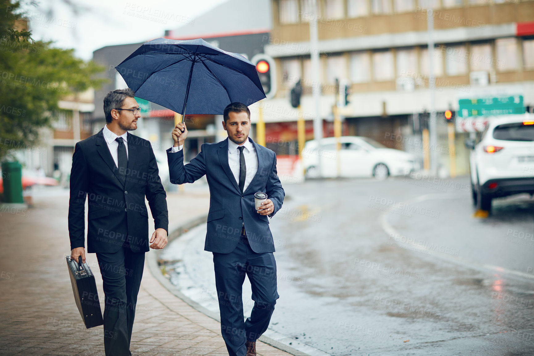 Buy stock photo Shot of two corporate businessmen travelling through the city on a rainy day