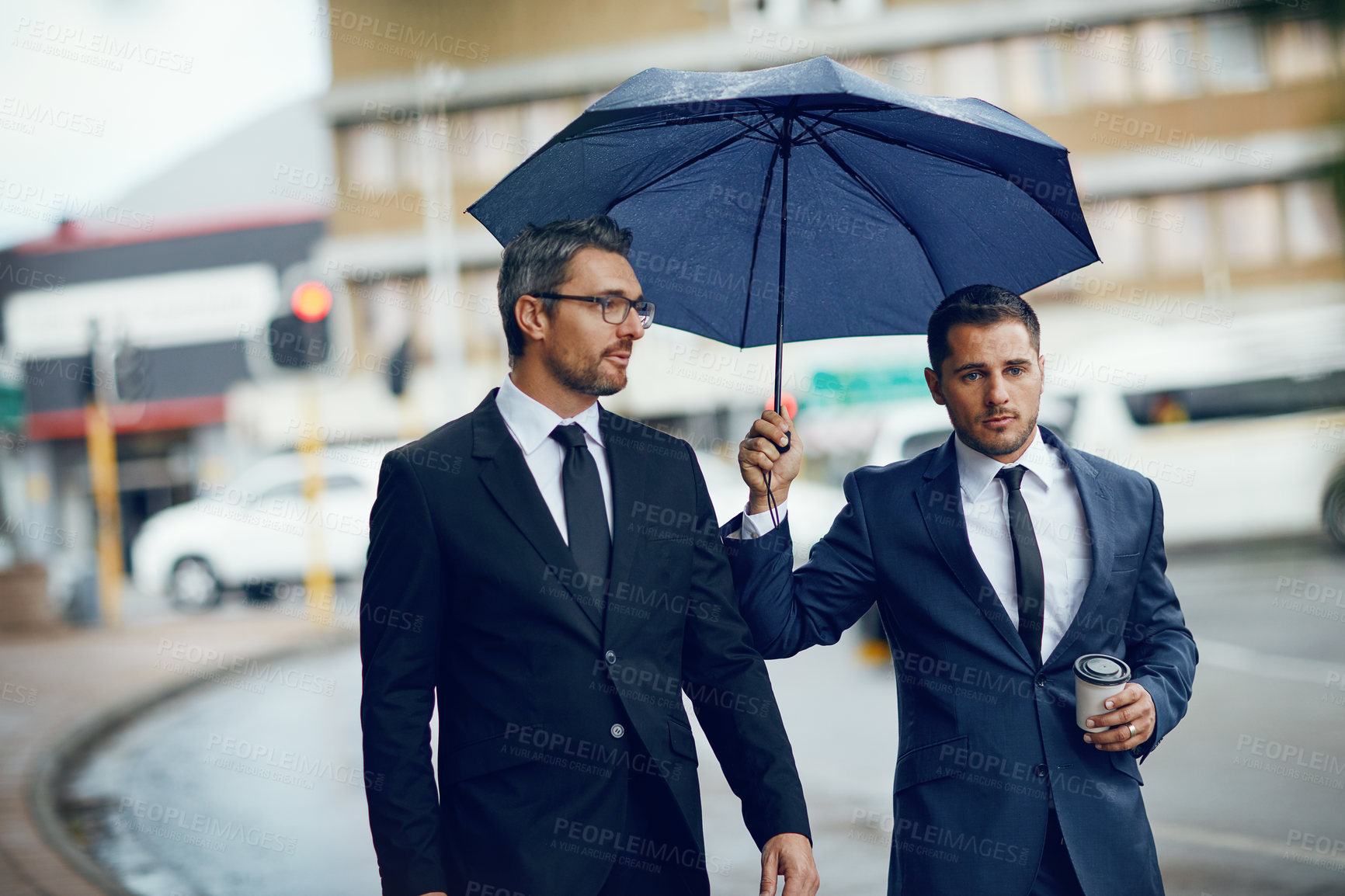 Buy stock photo Shot of two corporate businessmen travelling through the city on a rainy day