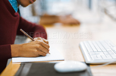 Buy stock photo Shot of a unrecognizable student writing down notes while working on a computer in a library