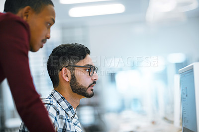 Buy stock photo Shot of two young focused students working o a computer together inside of a library