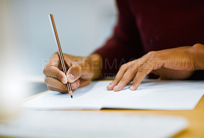 Buy stock photo Shot of a unrecognizable student writing down notes while working on a computer in a library