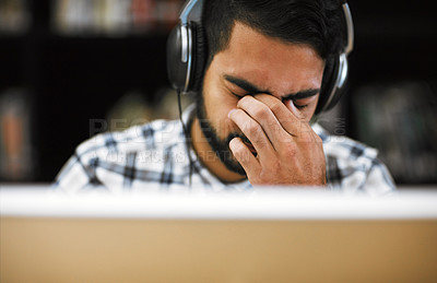 Buy stock photo Man, university student and eye strain on computer with headphones in library for internet, online error and research. Male person, tired and burnout or headache with assignment deadline and study