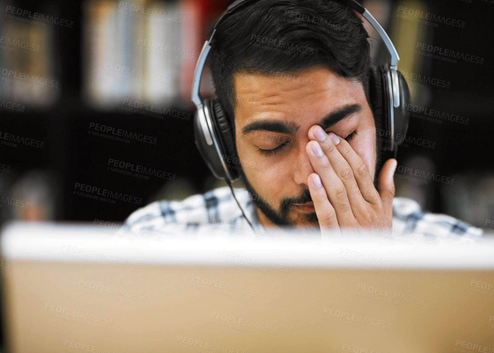 Buy stock photo Closeup shot of a stressed out young man working on a computer while listening to music with his eyes closed