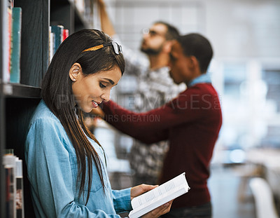 Buy stock photo Shot of a group young students standing in a library picking out books to read