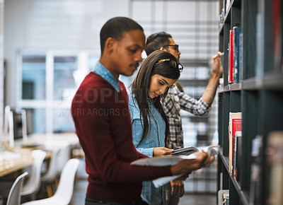 Buy stock photo Shot of a group young students standing in a library picking out books to read