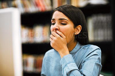 Buy stock photo Shot of a university student yawning while working on a computer in the library at campus
