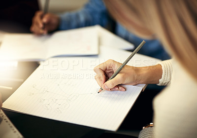 Buy stock photo Shot of a group of unrecognizable people making notes on paper while being seated around a table indoors