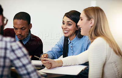 Buy stock photo Shot of a group of young cheerful students working together and making notes while being seated around a table