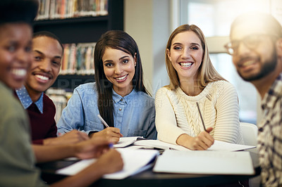 Buy stock photo Shot of a group of young cheerful students working together and making notes while being seated around a table and looking at the camera