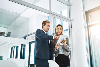 Buy stock photo Shot of two businesspeople discussing something on a digital tablet