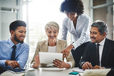 Buy stock photo Shot of a group of businesspeople discussing something on a digital tablet in a meeting