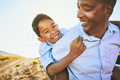 Buy stock photo Shot of a cheerful father giving his young son a piggyback ride outside