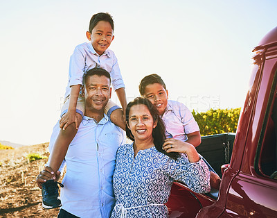 Buy stock photo Shot of a cheerful family posing for a portrait together outside next to a red pickup truck