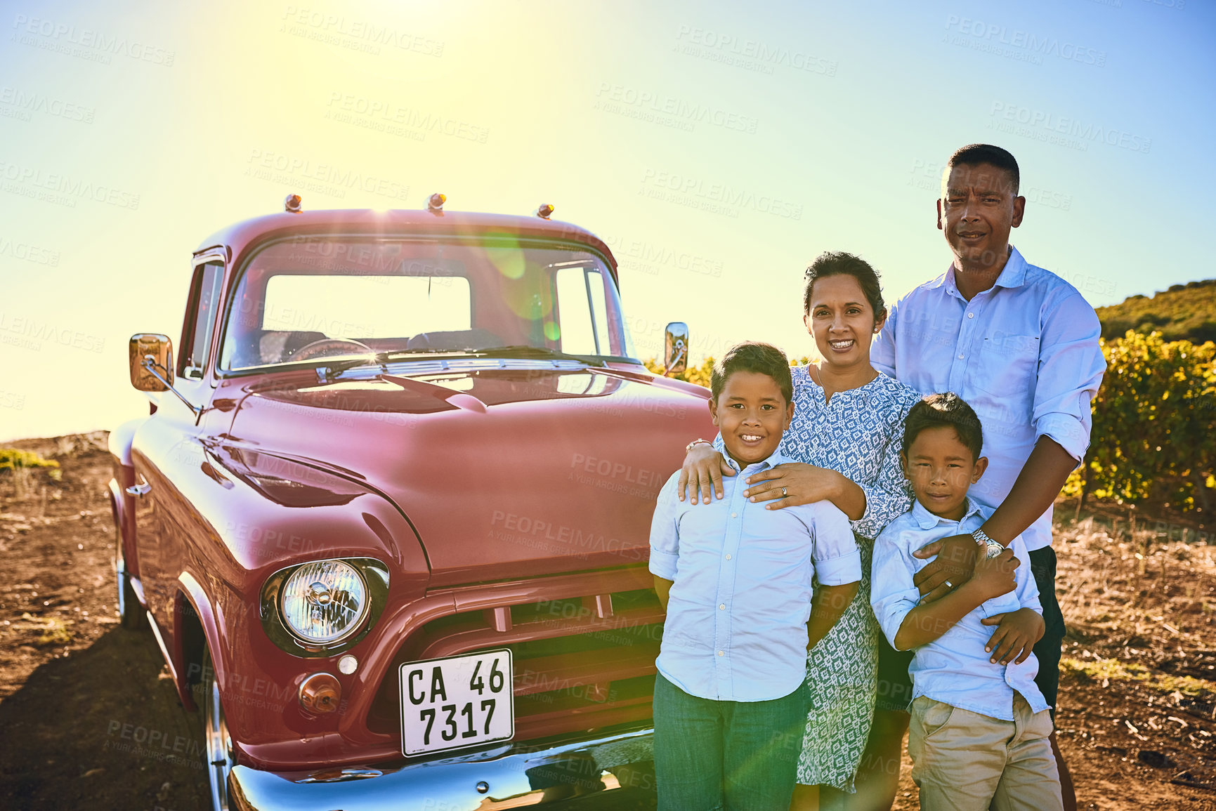 Buy stock photo Shot of a cheerful family posing for a portrait together outside next to a red pickup truck