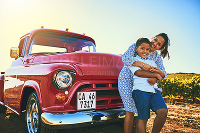 Buy stock photo Shot of a cheerful mother holding her young son and  spending quality time together while standing next to a red pickup truck outside