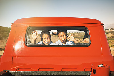 Buy stock photo Shot of two young cheerful boys smiling and waving from the back of a red pickup truck while looking into the camera