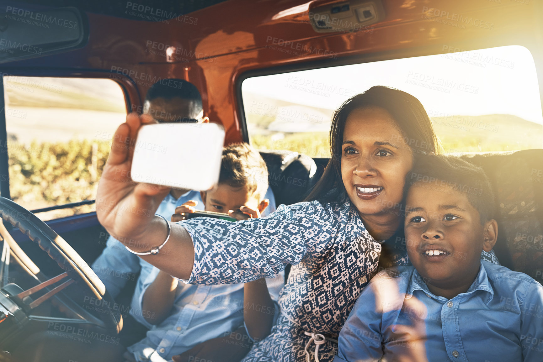 Buy stock photo Shot of a cheerful young family driving in a red pickup truck on a rural road while taking a self portrait on a cellphone together