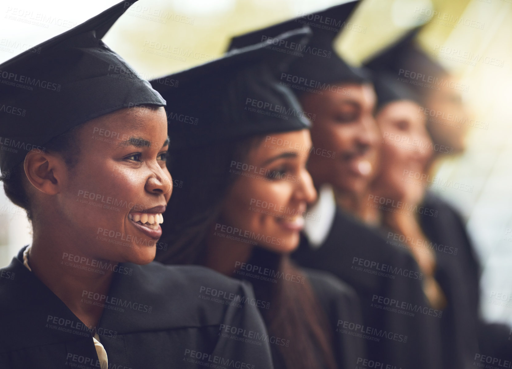 Buy stock photo Shot of a group of fellow students standing in a row on graduation day