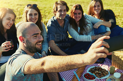Buy stock photo Shot of a group of friends taking a selfie while having a picnic together outdoors