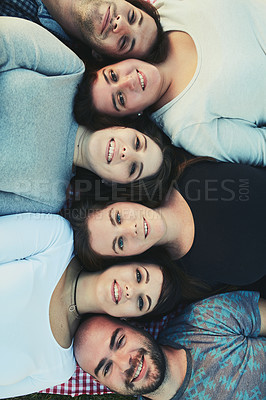 Buy stock photo Portrait of a group of friends lying down with their heads together outdoors
