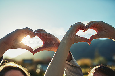 Buy stock photo Shot of two unrecognisable people making heart shapes with their hands outdoors