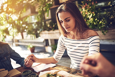 Buy stock photo Shot of creative employees holding hands and praying before breakfast outdoors