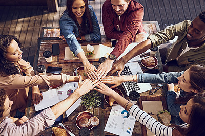 Buy stock photo High angle shot of a group of creative workers piling their hands while out on a business lunch