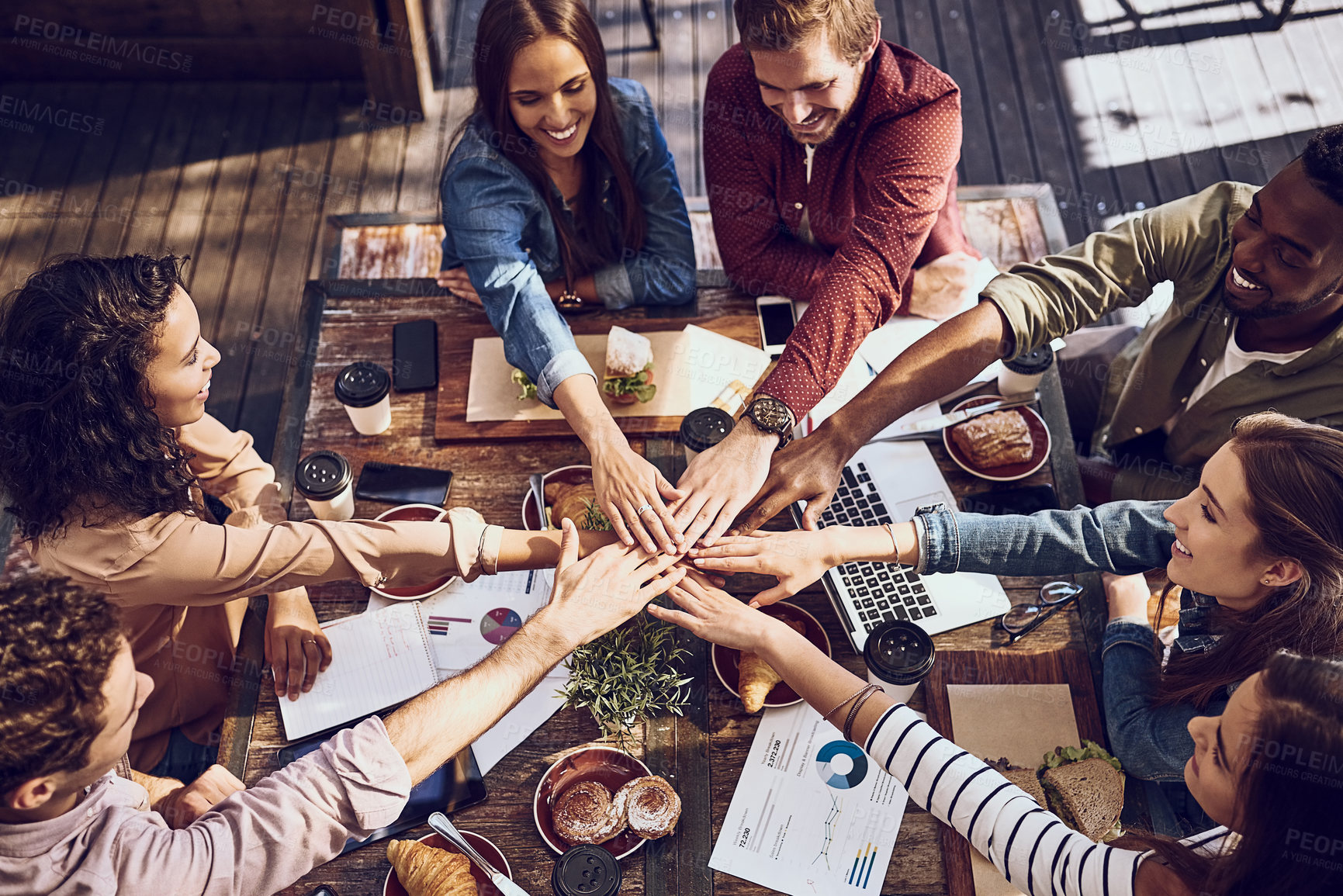 Buy stock photo High angle shot of a group of creative workers piling their hands while out on a business lunch