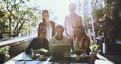 Buy stock photo Shot of a team of colleagues using a laptop together during a meeting at an outdoor cafe