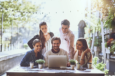 Buy stock photo Shot of a team of colleagues using a laptop together during a meeting at an outdoor cafe