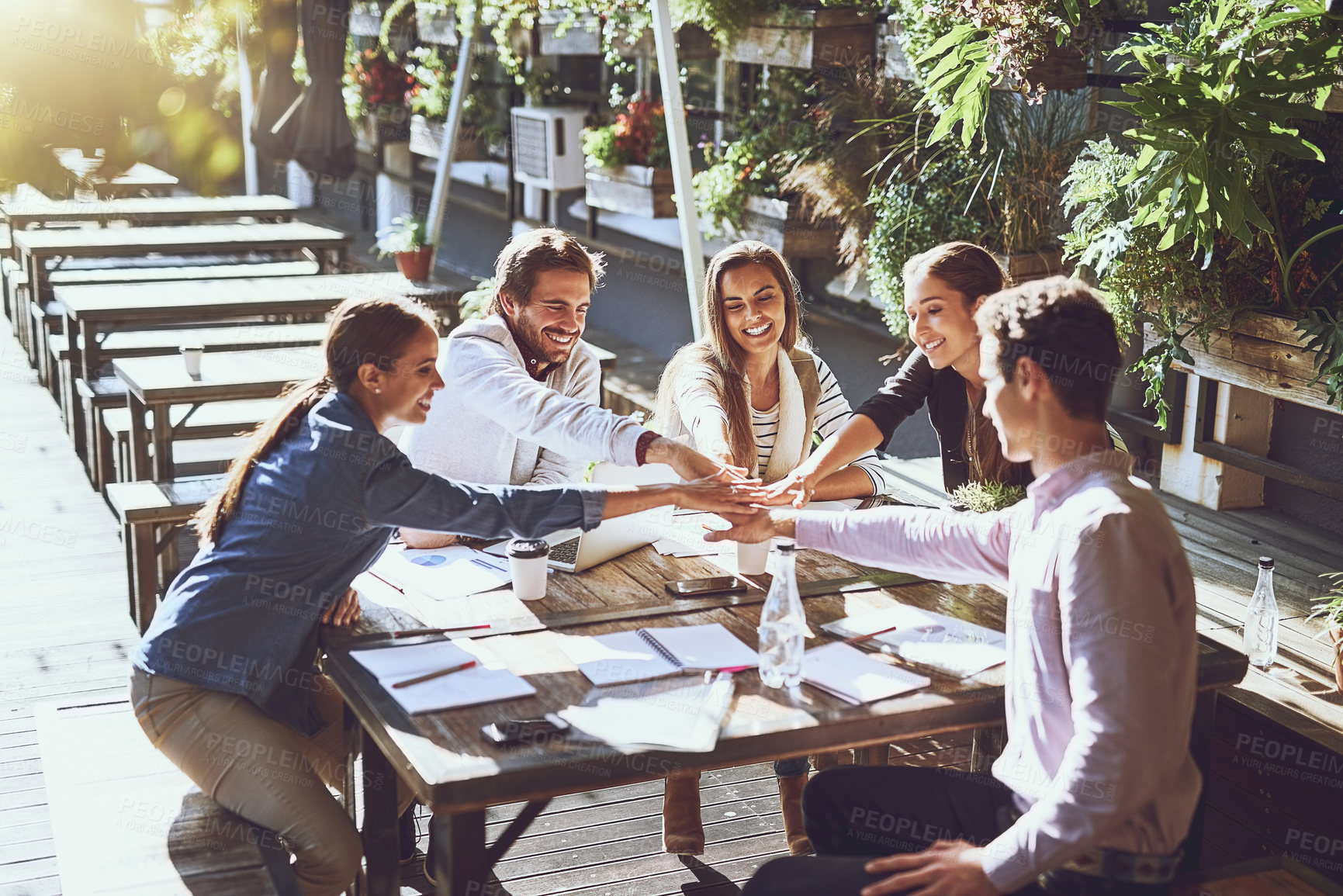 Buy stock photo Shot of a group of colleagues joining hands in agreement during a meeting at an outdoor cafe