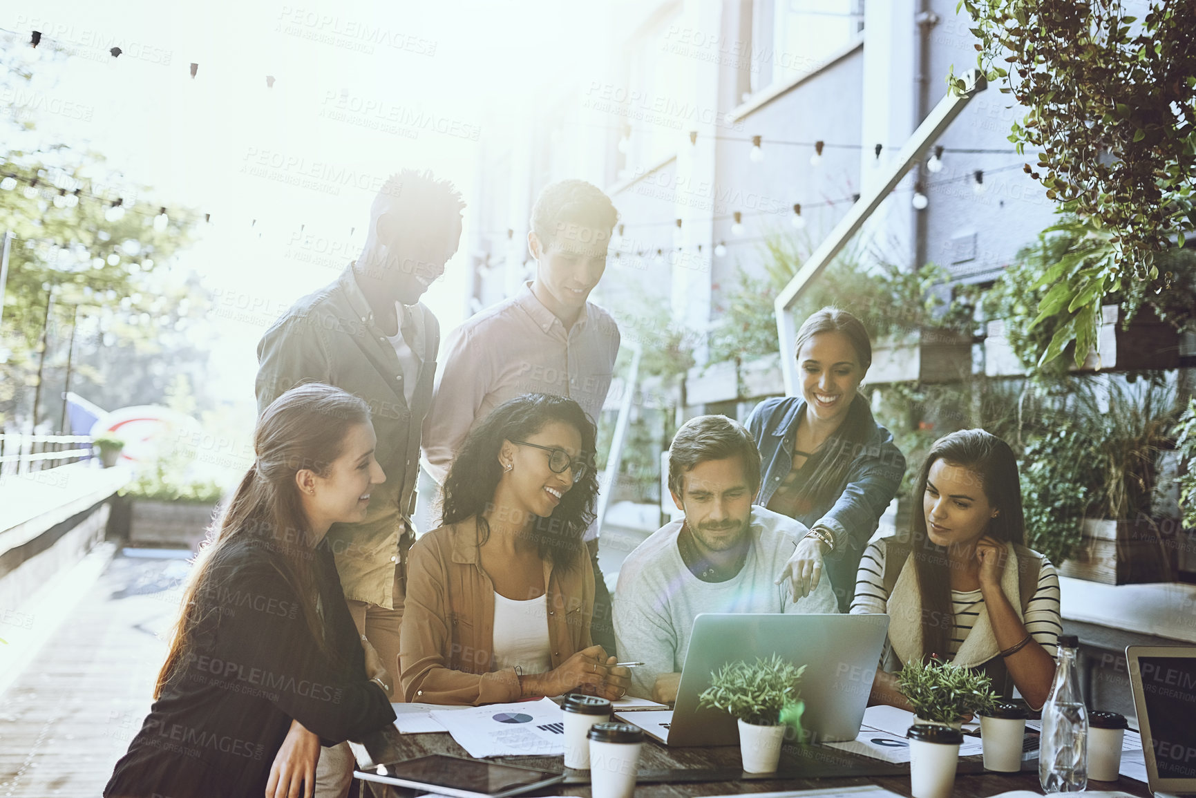 Buy stock photo Shot of a team of colleagues using a laptop together during a meeting at an outdoor cafe